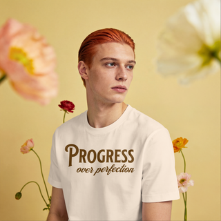 Person wearing a t-shirt with 'Progress over perfection' text against a floral background